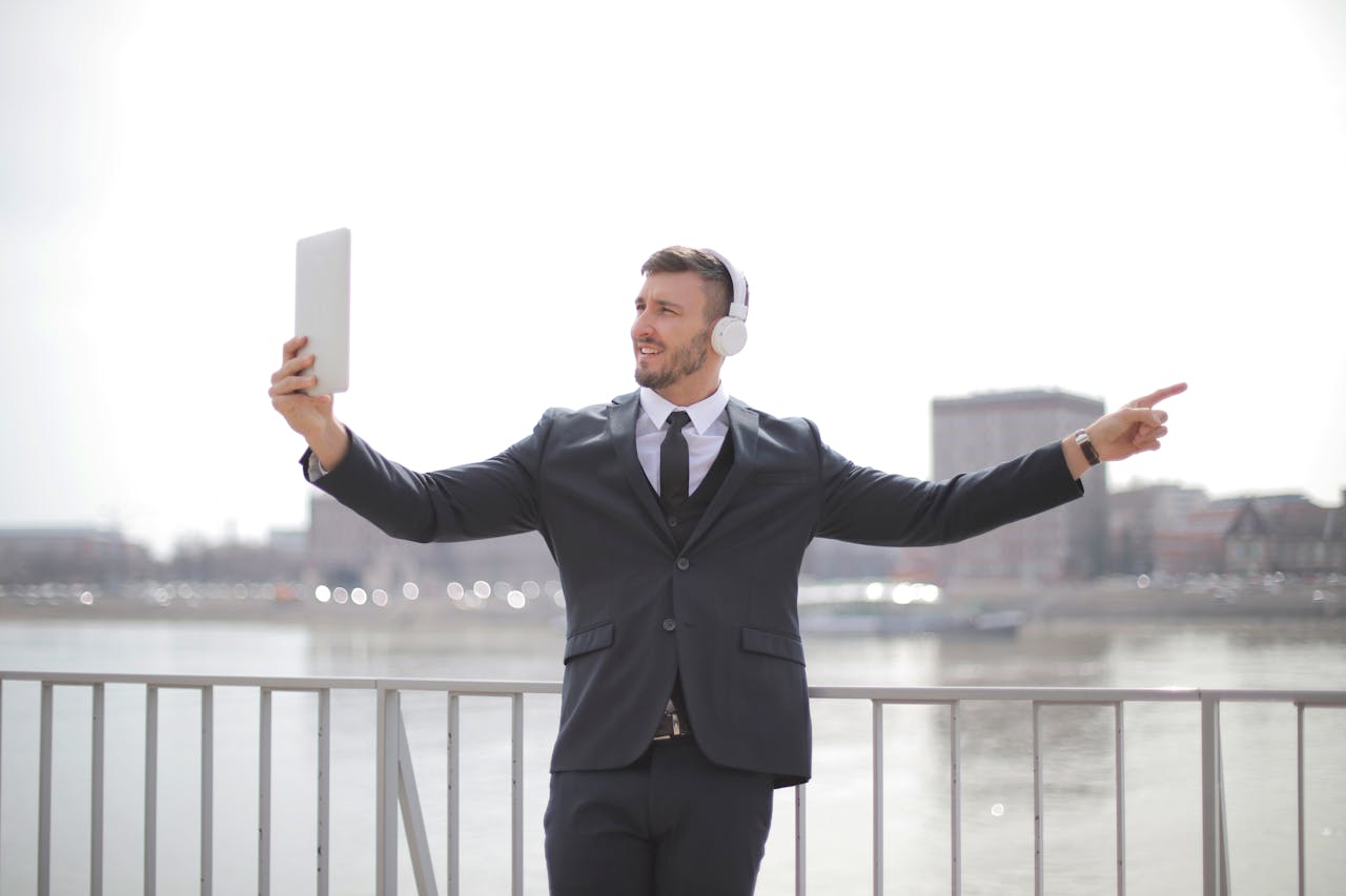 Mastering the First Impression: Your intriguing post title goes here Businessman in formal attire using a tablet for a video call while standing by a river.