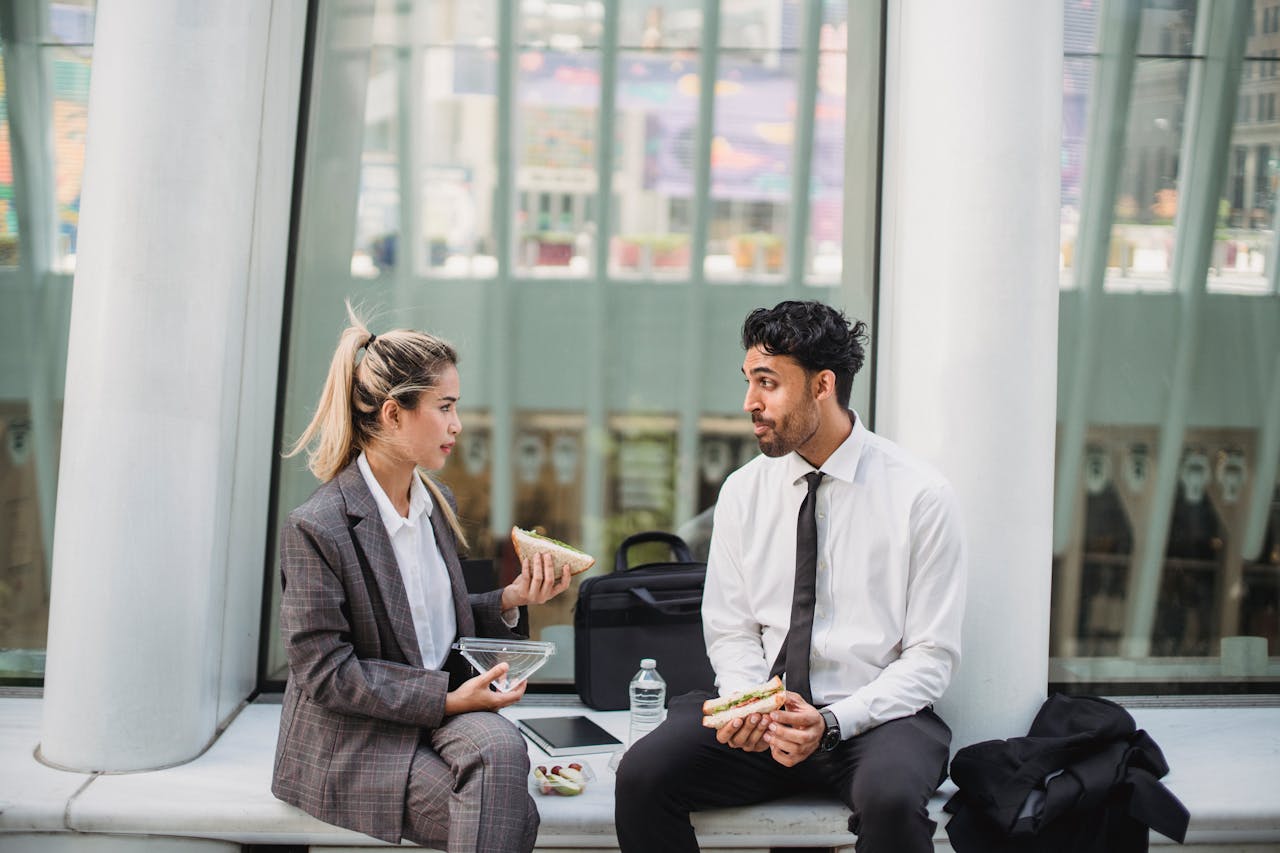Services Two professionals in a modern office enjoying a lunch break and engaging in conversation.