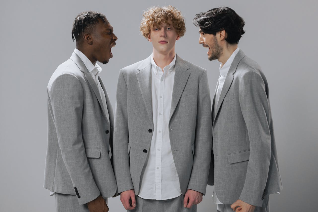 Services Three men in gray suits demonstrating conflict in a professional setting.
